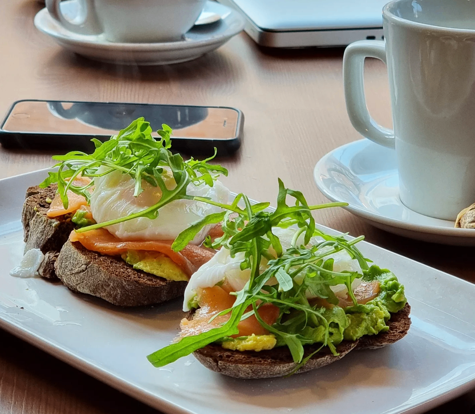 Smoked salmon, avocado and poached egg on sourdough toast with rocket, served with coffee